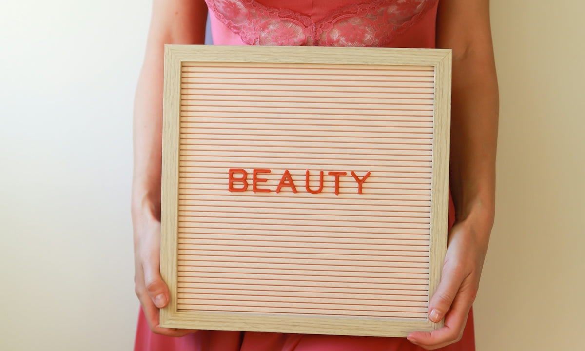 A woman in pink holds a sign that says beauty.