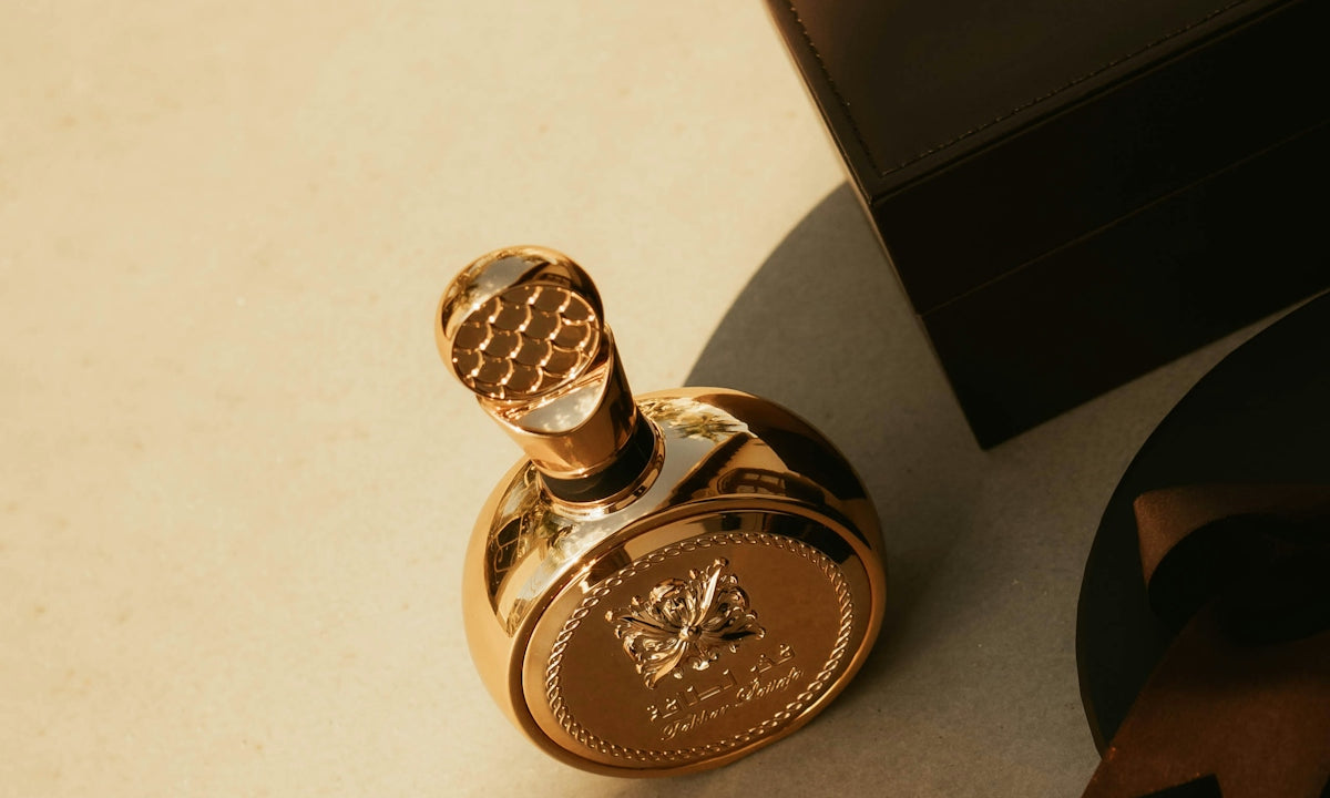 A gold perfume bottle with a dark box