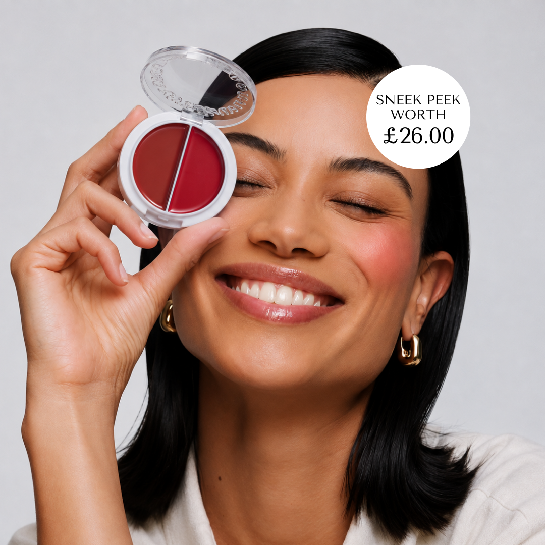A woman with closed eyes and a smile holds a round dual-pan blush compact next to her face. The compact contains deep rosy red and berry-toned shades in a white case. Cohorted subscription beauty box, KVD beauty, sneak peek, uk